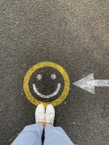 Shoes standing by a smiley face on the pavement