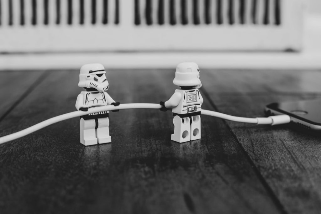 Lego storm troopers holding phone charger cord into phone