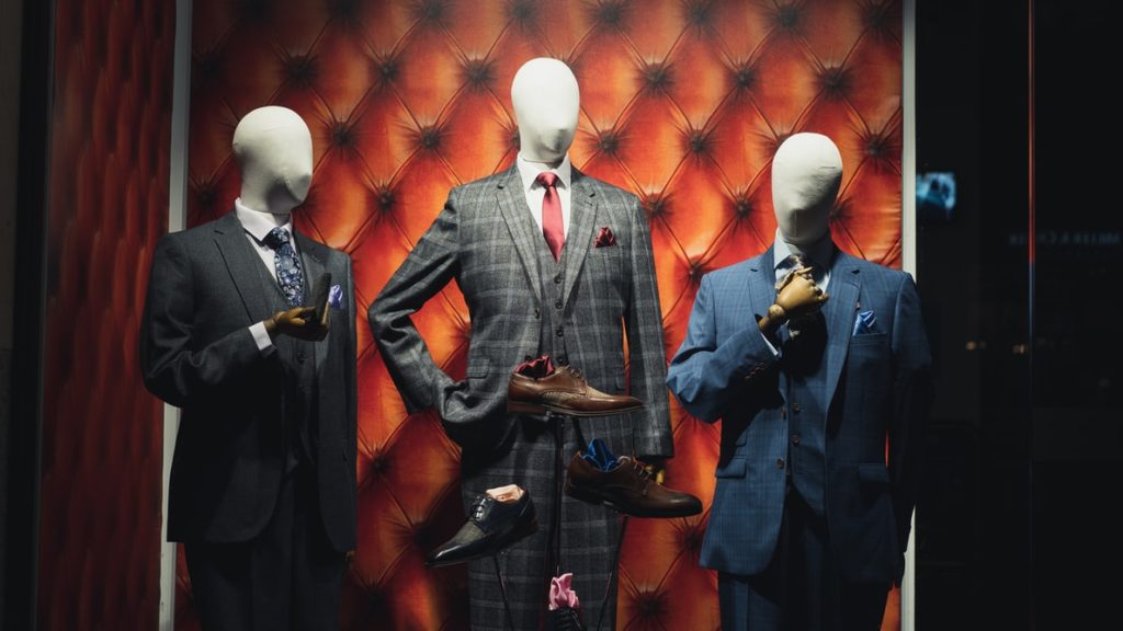 Three mannequins in a store window wearing suits