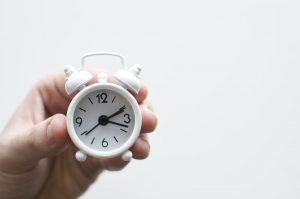 Hand holding small white clock